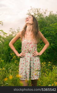 20s female enjoying summertime. Beautiful Young Woman standing in Meadow of Yellow Flowers.