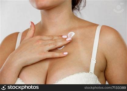 22 year old woman in underwear applying cream on her neck - isolatedy. concept for medicine and cosmetology