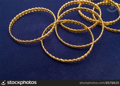 24k (24 carat) Turkish gold twist bracelet standing in a heap on a dark blue background in the gold store