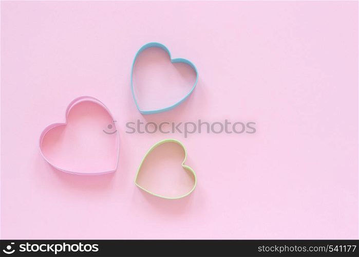 3 colorfed cutters cookies in heart shape on pastel pink background. Concept Valentine's card. Top view Copy space for text.. Colorfed cutters cookies in heart shape on pastel pink background. Concept Valentine's card. Top view Copy space for text