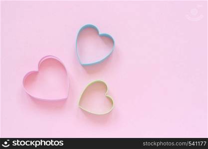 3 colorfed cutters cookies in heart shape on pastel pink background. Concept Valentine's card. Top view Copy space for text.. Colorfed cutters cookies in heart shape on pastel pink background. Concept Valentine's card. Top view Copy space for text