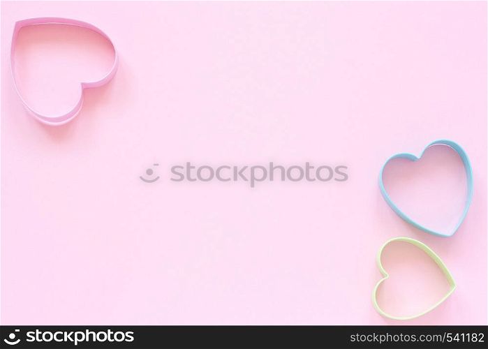 3 colorful cutters cookies in heart shape on pastel pink background. Concept Valentine's card. Top view Copy space for text.. Colorful cutters cookies in heart shape on pastel pink background. Concept Valentine's card. Top view Copy space for text