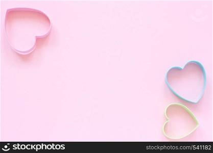 3 colorful cutters cookies in heart shape on pastel pink background. Concept Valentine's card. Top view Copy space for text.. Colorful cutters cookies in heart shape on pastel pink background. Concept Valentine's card. Top view Copy space for text