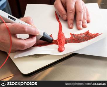 3-D printing pen creating a dragon shape. 3D printing pen working by melting ABS plastic to create a model of a dragon. 3-D printing pen creating a dragon shape
