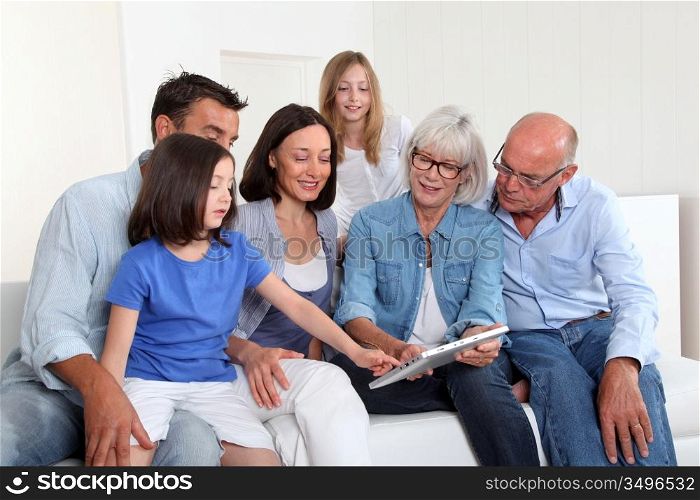 3-generation family sitting in couch with electronic tablet