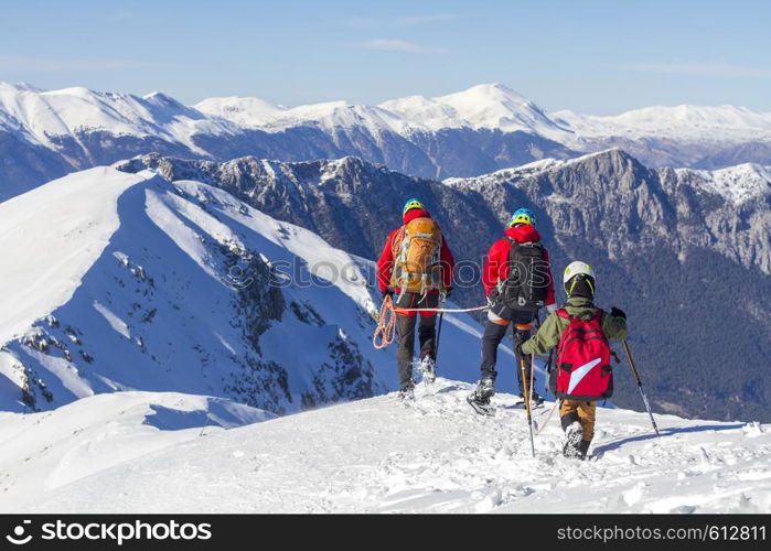 3 mountain climbers walk on snow in the mountains