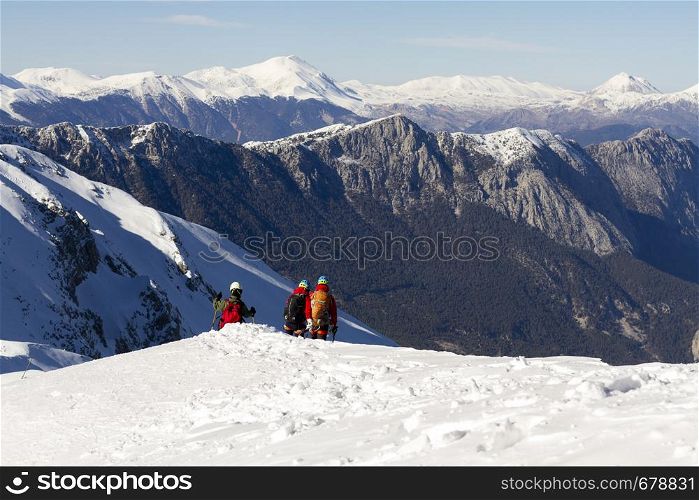 3 mountain climbers walk on snow in the mountains