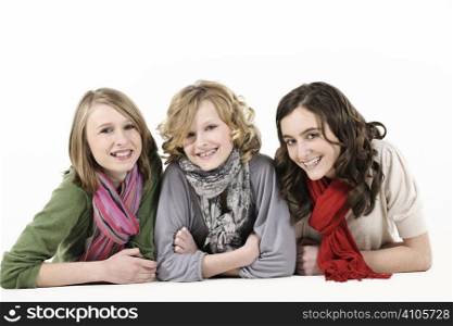 3 teenage girl friends lying down and smiling at camera