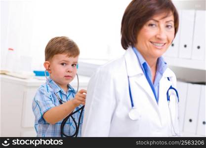 3 years old boy playing with senior female doctor at office.