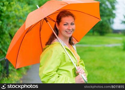 30-year-old smiling girl holding an umbrella under the rain