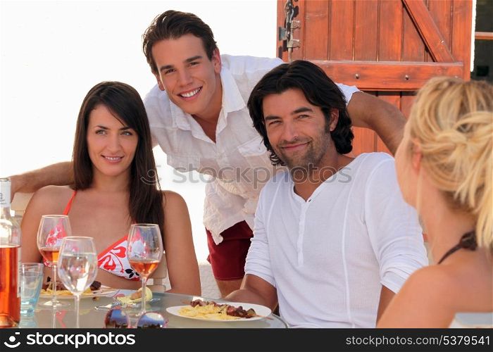 30 years old couple and a 20 years old man behind them posing outside at lunch time, summer scene