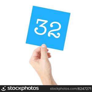 32 written on a card held by a hand