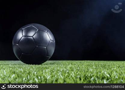 3D Illustration. Low-angle close-up of a black soccer ball on the green grass of the football ground against dark background for copy space