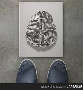 3d metal human brain icon on front of business man feet as concept