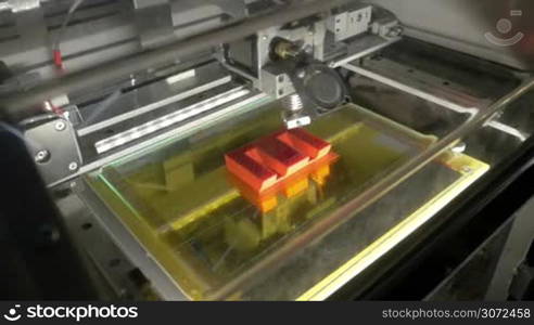 3D printer at work. Computer controlled machine printing letter E using the technology of laying down successive layers