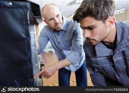 3d printer with two men looking at monitor screen