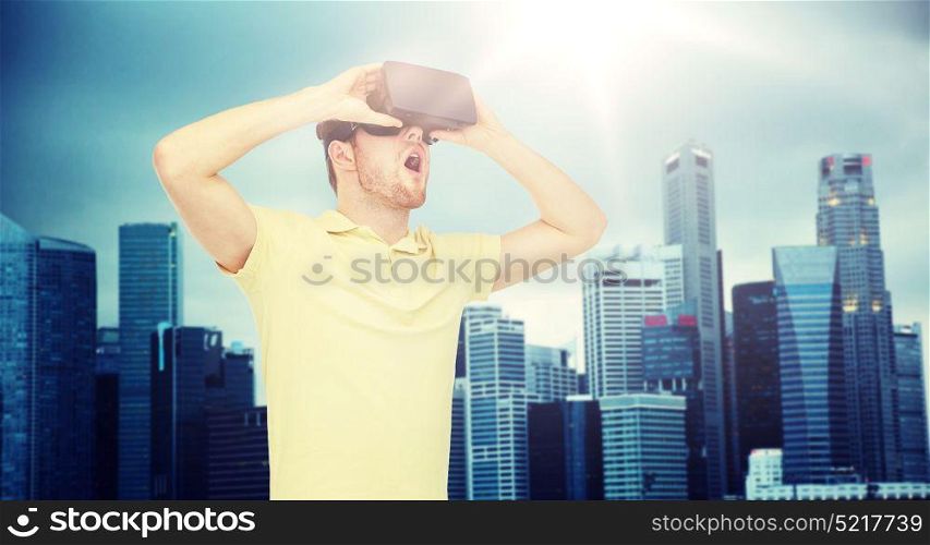 3d technology, virtual reality, entertainment and people concept - happy young man with virtual reality headset or 3d glasses playing game over singapore city skyscrapers background. happy man in virtual reality headset or 3d glasses