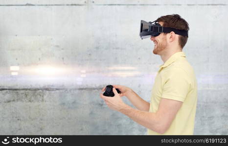 3d technology, virtual reality, entertainment and people concept - happy young man with virtual reality headset or 3d glasses playing with game controller gamepad over gray concrete wall background