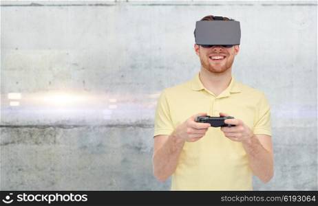 3d technology, virtual reality, entertainment and people concept - happy young man with virtual reality headset or 3d glasses playing with game controller gamepad over gray concrete wall background