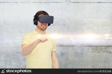 3d technology, virtual reality, entertainment and people concept - happy young man with virtual reality headset or 3d glasses playing game over gray concrete wall background