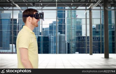 3d technology, virtual reality, entertainment and people concept - happy young man with virtual reality headset or 3d glasses playing game over industrial empty room and city panorama background