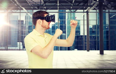 3d technology, virtual reality, entertainment and people concept - young man with virtual reality headset playing game and fighting over empty industrial room and city panorama background. man in virtual reality headset or 3d glasses