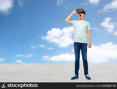 3d technology, virtual reality, entertainment, cyberspace and people concept - amazed young man with virtual reality headset or 3d glasses looking at something over blue sky and clouds background
