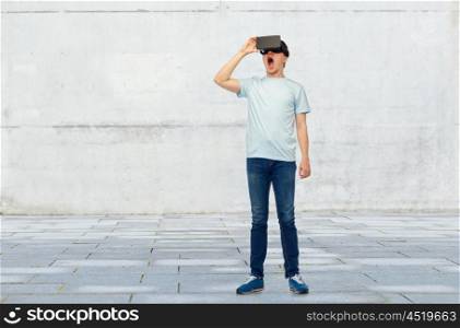 3d technology, virtual reality, entertainment, cyberspace and people concept - amazed young man with virtual reality headset or 3d glasses over street background