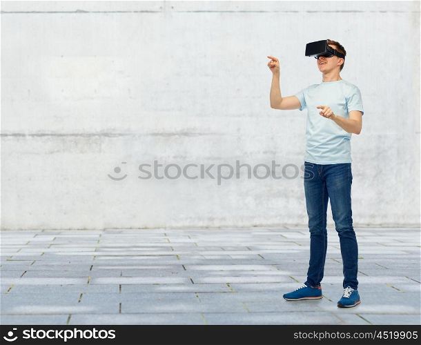 3d technology, virtual reality, entertainment, cyberspace and people concept - happy young man with virtual reality headset or 3d glasses playing game and touching something over street background