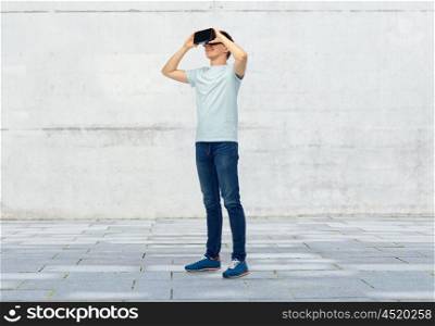 3d technology, virtual reality, entertainment, cyberspace and people concept - happy young man with virtual reality headset or 3d glasses over street background