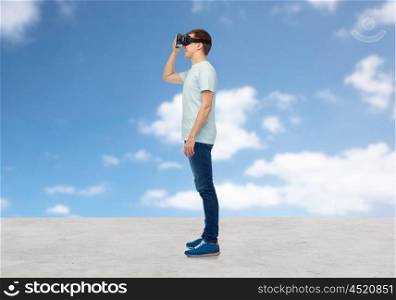 3d technology, virtual reality, entertainment, cyberspace and people concept - happy young man with virtual reality headset or 3d glasses looking at something over blue sky and clouds background
