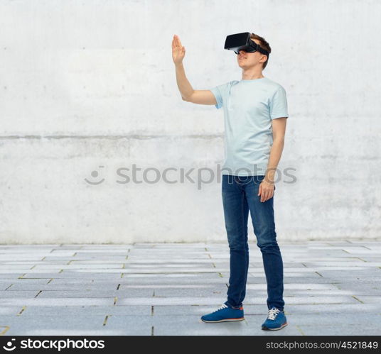 3d technology, virtual reality, entertainment, cyberspace and people concept - happy young man with virtual reality headset or 3d glasses playing game and touching something over street background