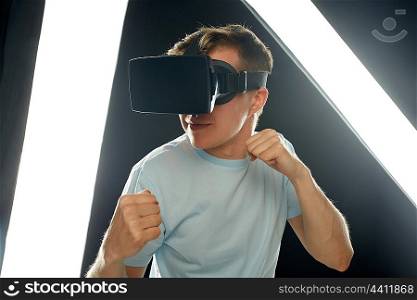 3d technology, virtual reality, entertainment, cyberspace and people concept - young man with virtual reality headset or 3d glasses playing game and fighting