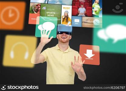 3d technology, virtual reality, entertainment, media and people concept - happy young man in virtual reality headset or 3d glasses playing game over black background with screens and computer icons