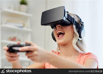 3d technology, virtual reality, gaming, entertainment and people concept - happy young woman in virtual reality headset or 3d glasses and headphones playing video game with controller gamepad at home