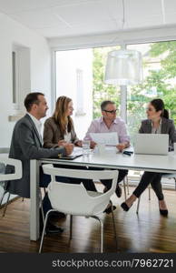 4 business men and women participating in a meeting in beautiful environment, might be a startup company