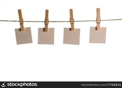 4 Note paper cards hanging with wooden clip or clothespin on rope string peg isolated on white. Note paper cards on rope