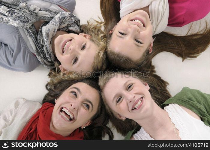 4 teenage girl friends lying down and smiling up at camera