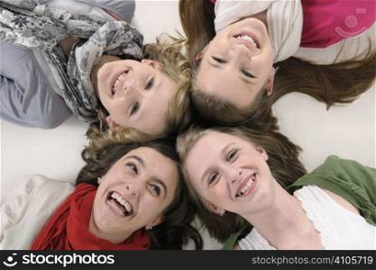 4 teenage girl friends lying down and smiling up at camera