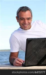 40 years old man doing computer behind the sea