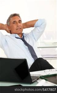 50-55 years old man dressed in shirt and tie is relaxing in his office