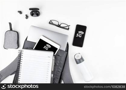 5G network, high-speed mobile Internet, new generation networks concept. Creative top view flat lay of open backpack with laptop and tablet inside, smartphone copy space white background minimal style