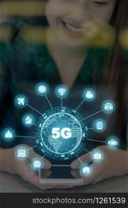 5G technology with various icon internet of thing over hand using the smart mobile phone on the desk beside the glass in workplace or co-working space or modern office, IOT and Connectivity concept