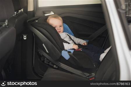 6 months old baby boy sitting in child car seat
