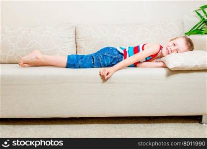 6 years old boy lying on the couch in the living room