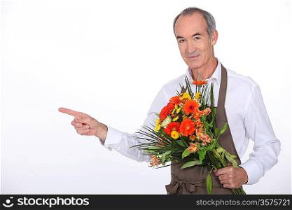 65 years old male florist taking a flowers bouquet and pointing finger on something