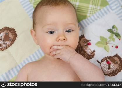 7 month old baby girl in crib with fingers in her mouth