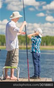 7-year-old son helps his father to fish in the lake