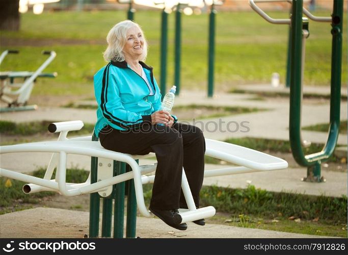 70 years old Healthy Senior Woman Resting after Exercises Outdoors in the Bright Autumn Evening