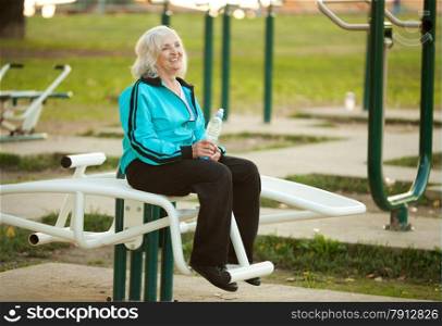 70 years old Healthy Senior Woman Resting after Exercises Outdoors in the Bright Autumn Evening